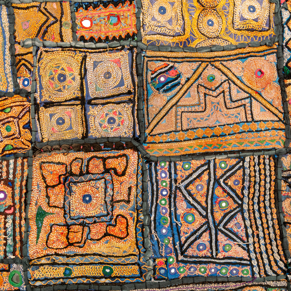 Vintage embroidered textile wall hanging with intricate handwork and visible signs of age.