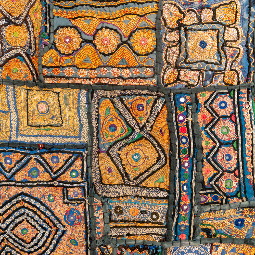 Vintage embroidered textile wall hanging with intricate handwork and visible signs of age.