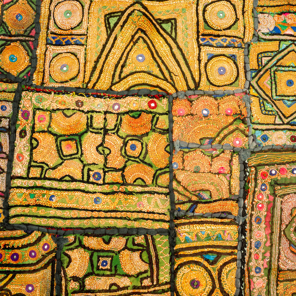 Vintage embroidered textile wall hanging with intricate handwork and visible signs of age.